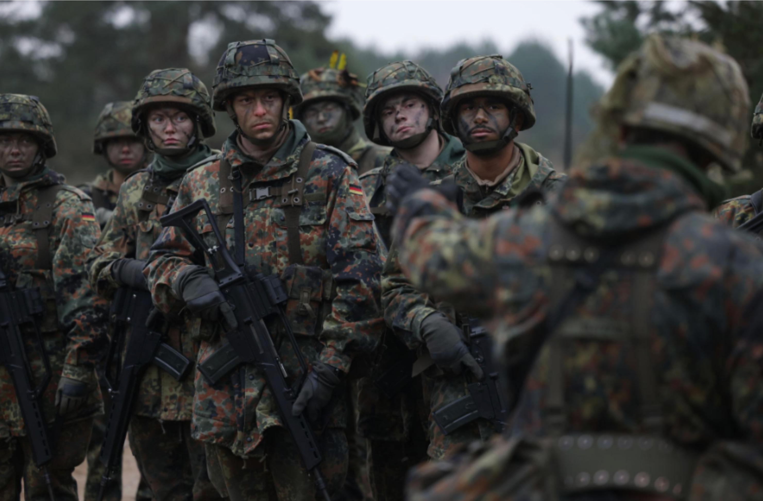 German soldiers in uniform during a military briefing or field exercise.